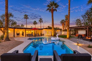 A swimming pool with lounge chairs, a swan float, and palm trees.