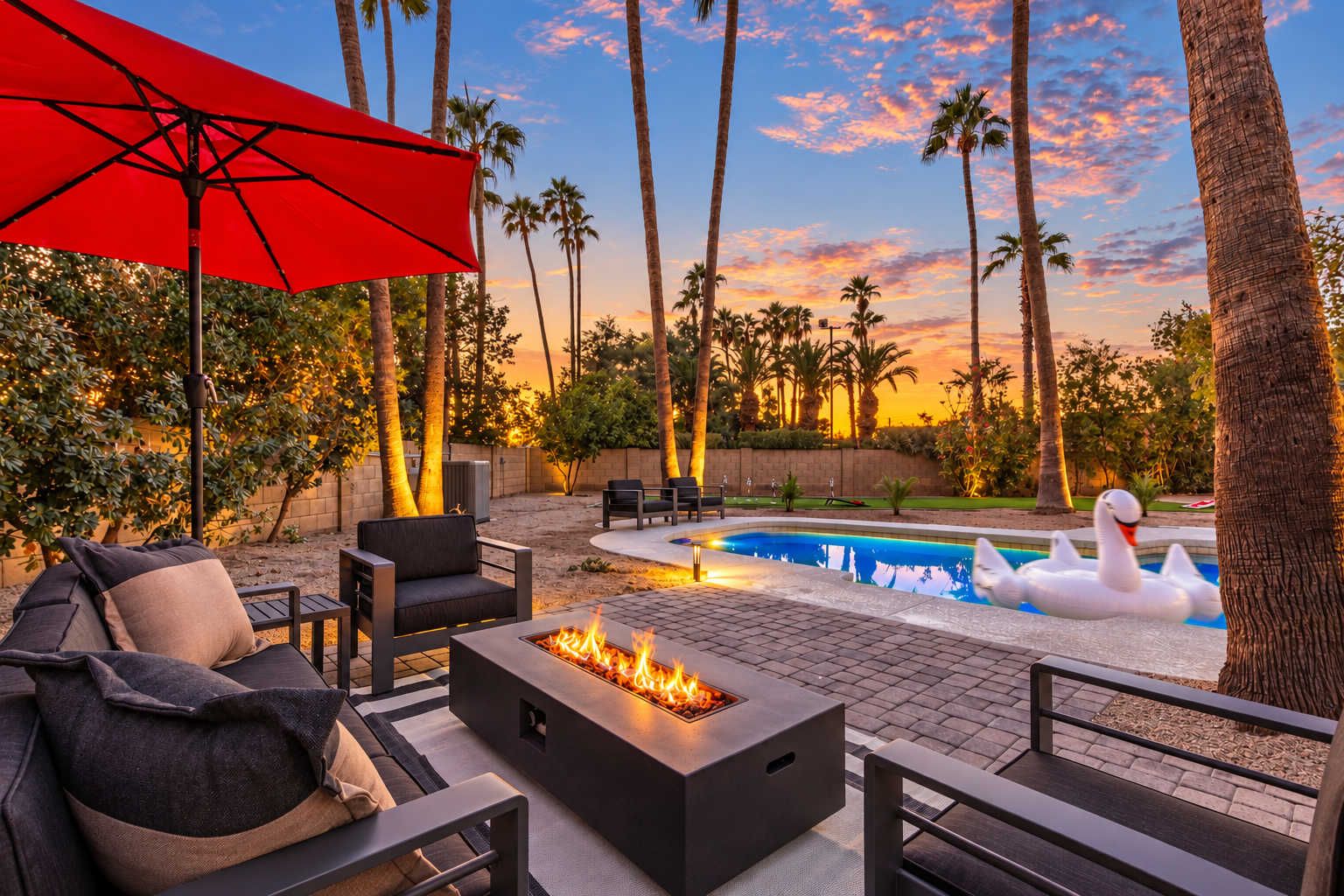An outdoor patio with a fire pit, seating, and a pool with a swan float.