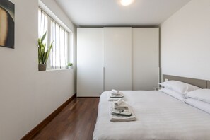 A hotel room with a bed, a window with curtains, a plant, and a wardrobe. - BnButler - Celio, 11 (Milano)