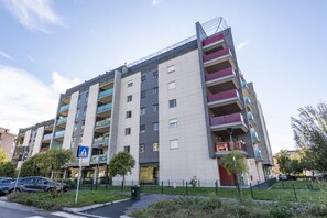 A multi-story residential building with balconies, a pedestrian crossing sign, and a parking area. - BnButler - Celio, 11 (Milano)