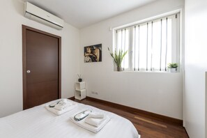 A hotel room with a bed, an air conditioner, a window with blinds, a painting, and a potted plant. - BnButler - Celio, 11 (Milano)