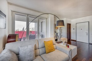 A modern living room with a sofa, a bookshelf, and a large window. - BnButler - Celio, 11 (Milano)
