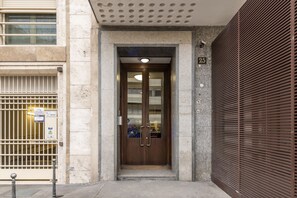 A building entrance with a double door, a security camera, and a numbered sign. - BnButler - De Amicis, 25 (Milano)