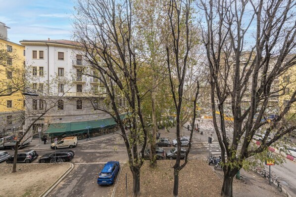 A street view with parked cars, trees, and buildings.
