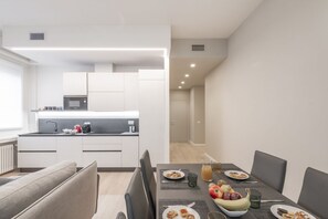 Une cuisine moderne avec des meubles blancs, un four à micro-ondes et un coin repas avec une table mise pour deux personnes.