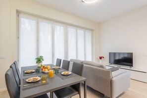 A modern living room with a dining area, a sofa, a TV, and a large window. - BnButler - De Amicis, 25 (Milano)