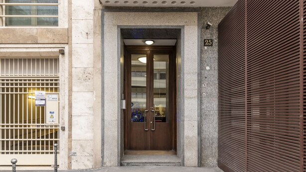 A building entrance with a double door, a security camera, and a numbered sign. - BnButler - De Amicis, 25 (Milano)