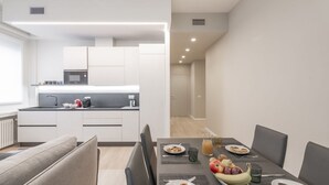 A modern kitchen with white cabinets, a microwave, and a dining area with a table set for two. - BnButler - De Amicis, 25 (Milano)