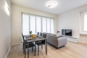 A modern living room with a dining table, sofa, TV, and large windows. - BnButler - De Amicis, 25 (Milano)