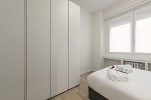 A bedroom with a bed, a wardrobe, and a window. - BnButler - De Amicis, 25 (Milano)