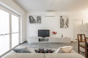 Una sala de estar moderna con un televisor de pantalla plana, un mueble blanco para entretenimiento y obras de arte en las paredes.