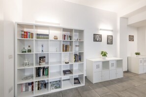 A modern library with white shelving units, books, decorative items, and a small white cabinet. - BnButler - Washington, 83 (Milano)