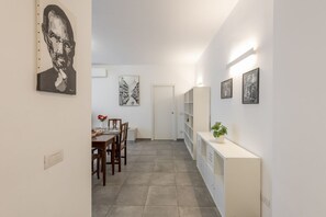 A hallway with a dining area, white walls, and artwork.