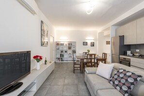 Una sala de estar moderna con una televisión de pantalla plana, un sofá y una zona de comedor con una mesa y sillas.
