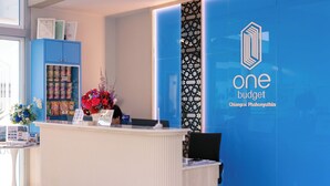 Un comptoir d’accueil avec un mur bleu orné du logo et du nom de l’entreprise « One Budget ».