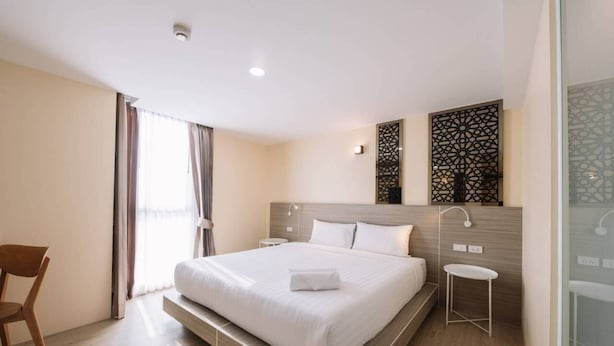 Habitació d'hotel moderna amb un llit gran, una taula petita i una cadira.
