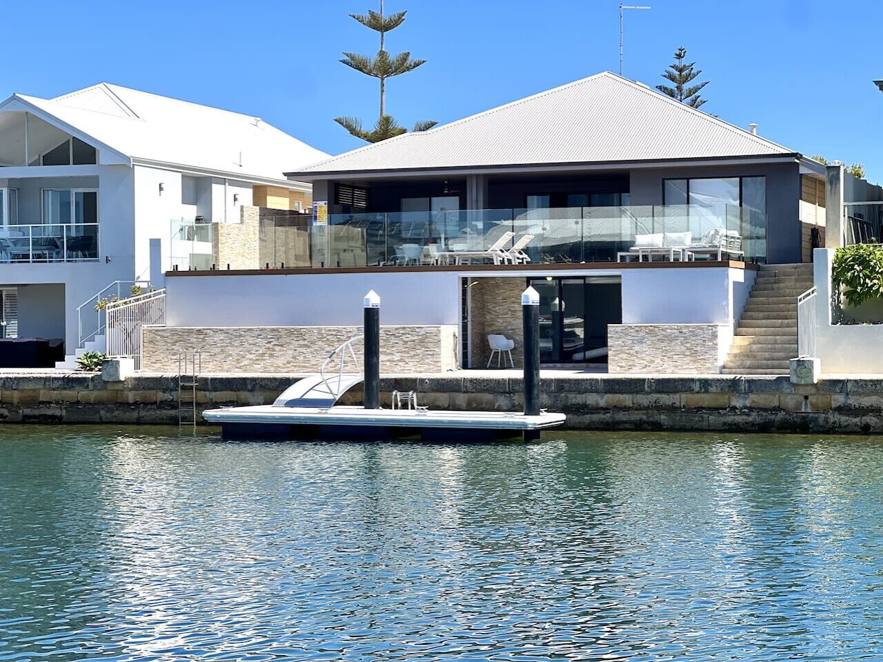 A modern house with a dock and a boat.