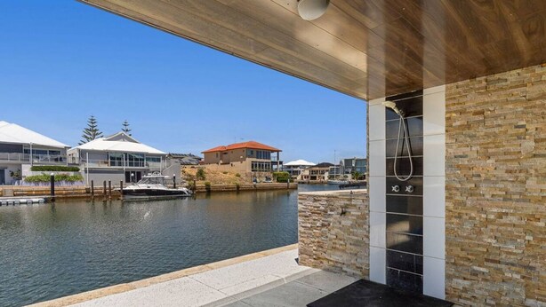 A waterfront hotel with a modern design, featuring a stone wall and a covered area with a shower. - Casa Cumpari in Wannanup (Wannanup)