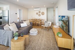 Een moderne woonkamer met een bank, salontafel en eethoek.