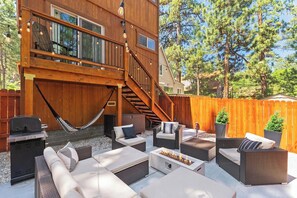 Eine Holzterrasse mit Gartenmöbeln, einem Grill und einer Feuerstelle.