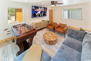 Ein Wohnzimmer mit Tischfußball, Fernseher, Sofa und Couchtisch.