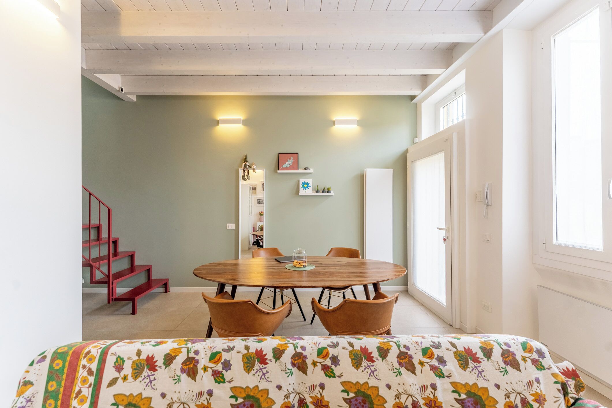 A dining area with a round table, four chairs, and a bench with a floral pattern.