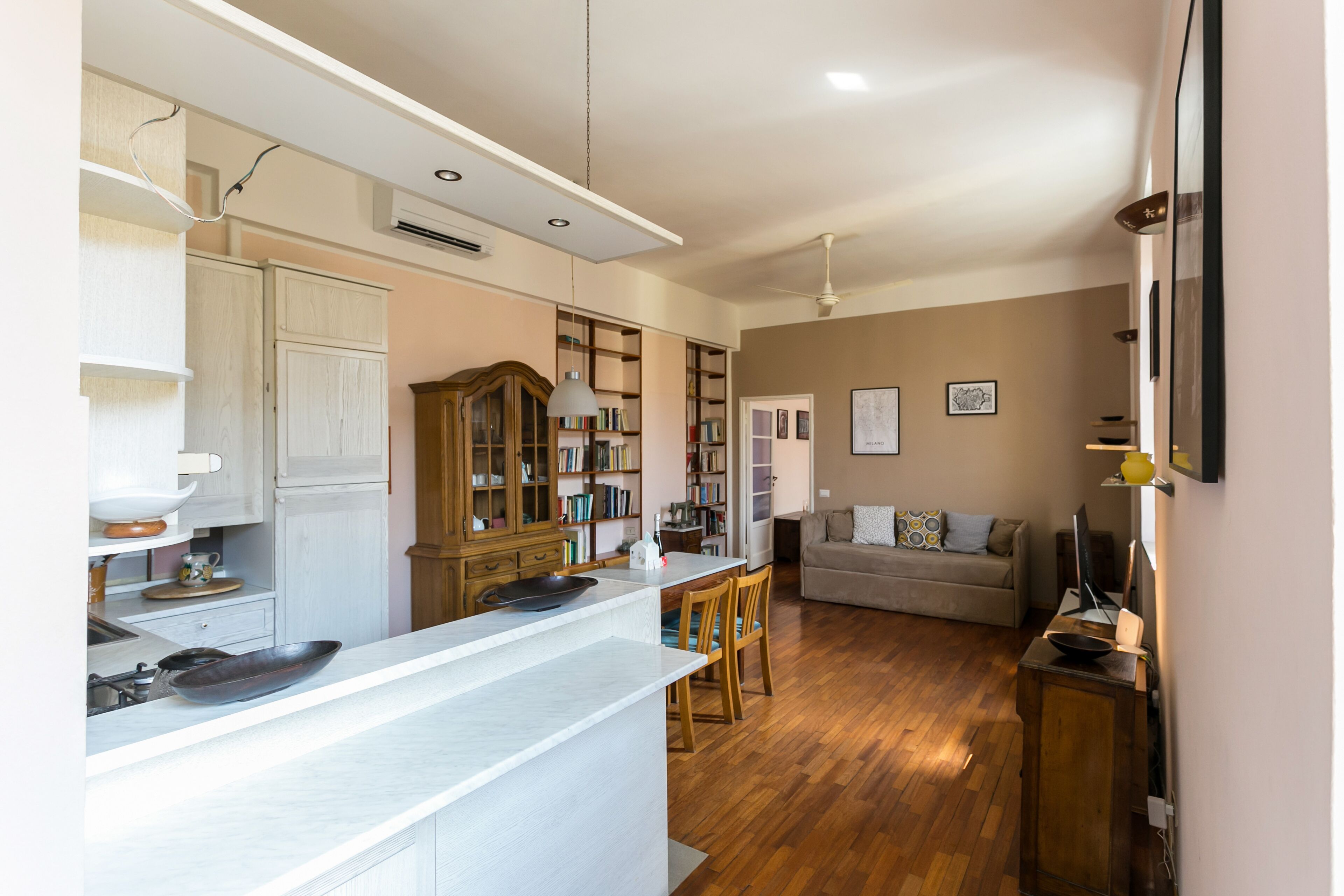 Una cocina moderna con armarios blancos, una mesa de comedor de madera y una zona de estar acogedora con sofá y televisor.