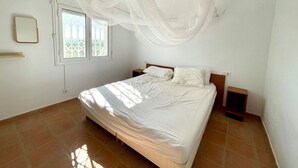 Une chambre à coucher avec un lit, une fenêtre et une table de chevet.