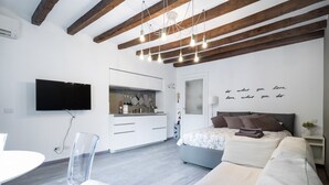 Een moderne slaapkamer met een groot bed, een nachtkastje en een tv aan de muur.