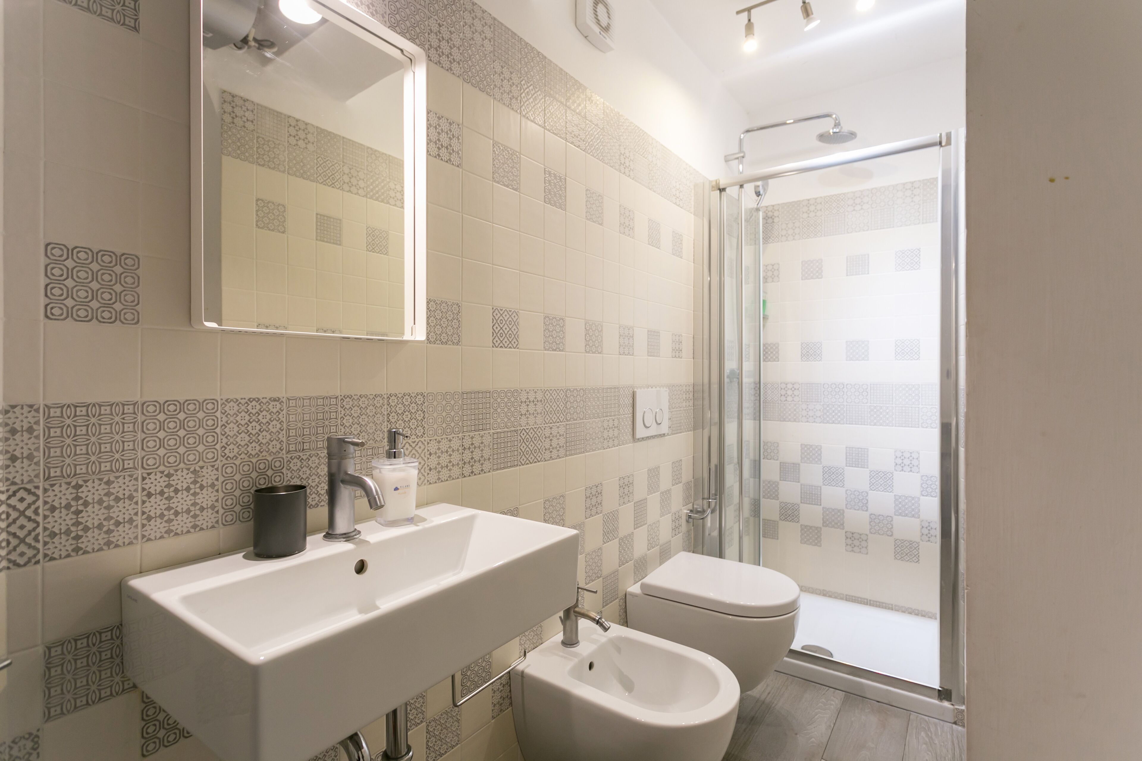 A bathroom with a sink, mirror, toilet, and shower.