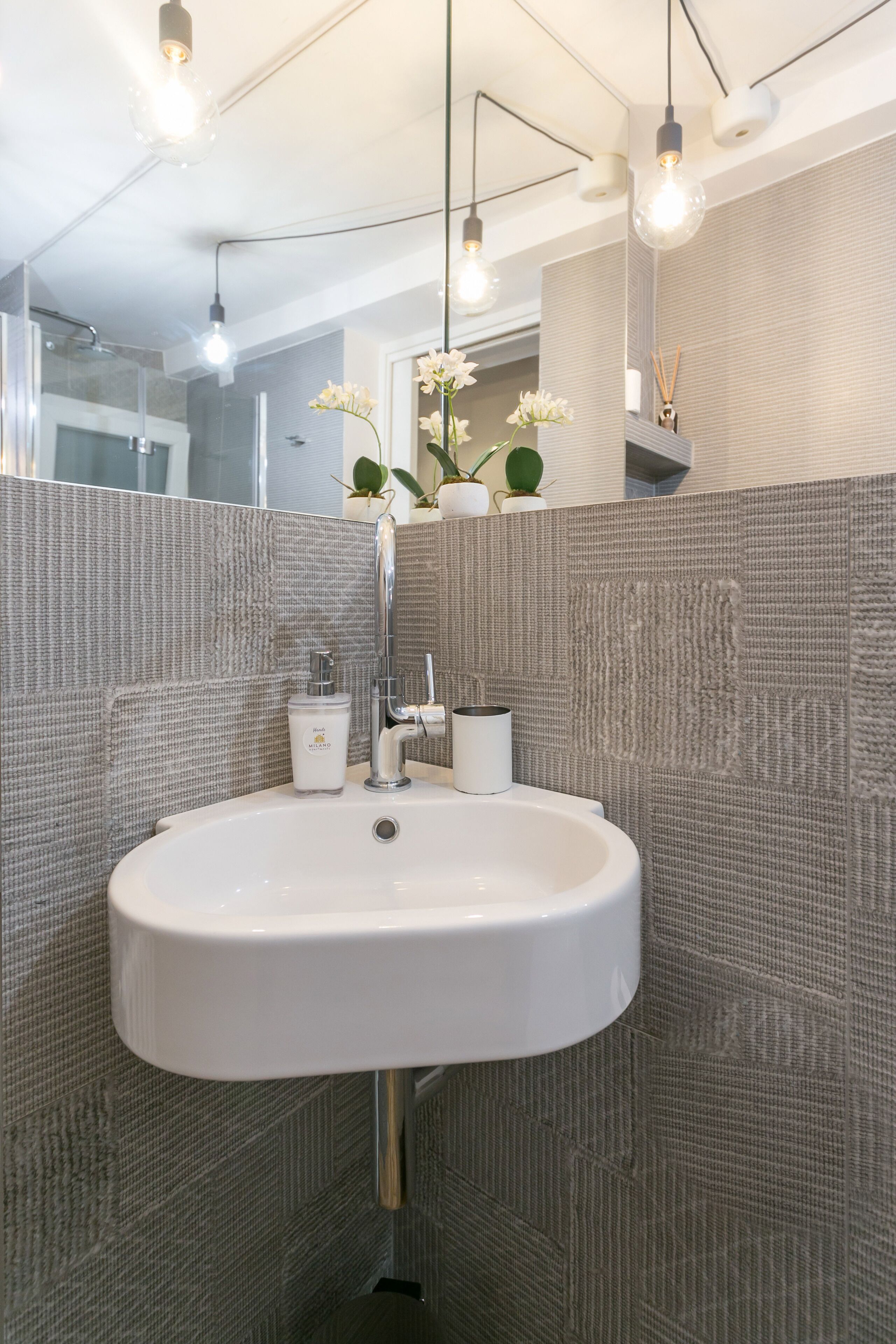 Ein modernes Badezimmer mit einem weißen Waschbecken, einem Spiegel und einer Duschkabine.