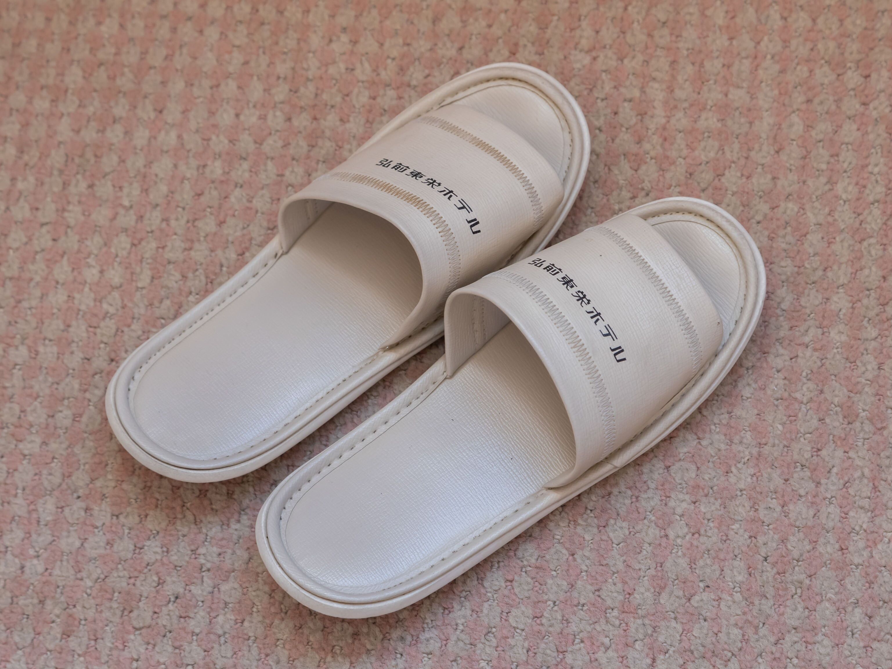 Un par de sandalias blancas con texto en la correa.