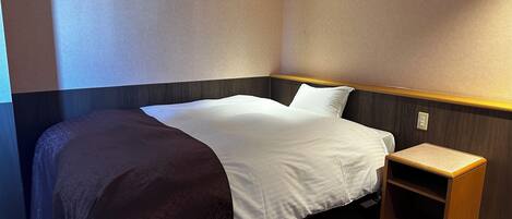 A hotel room with a bed, a bedside table, and a carpeted floor.