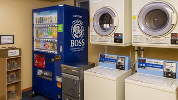 A laundromat with a Suntory Coffee Boss vending machine, two washing machines, and a coin-operated washer.