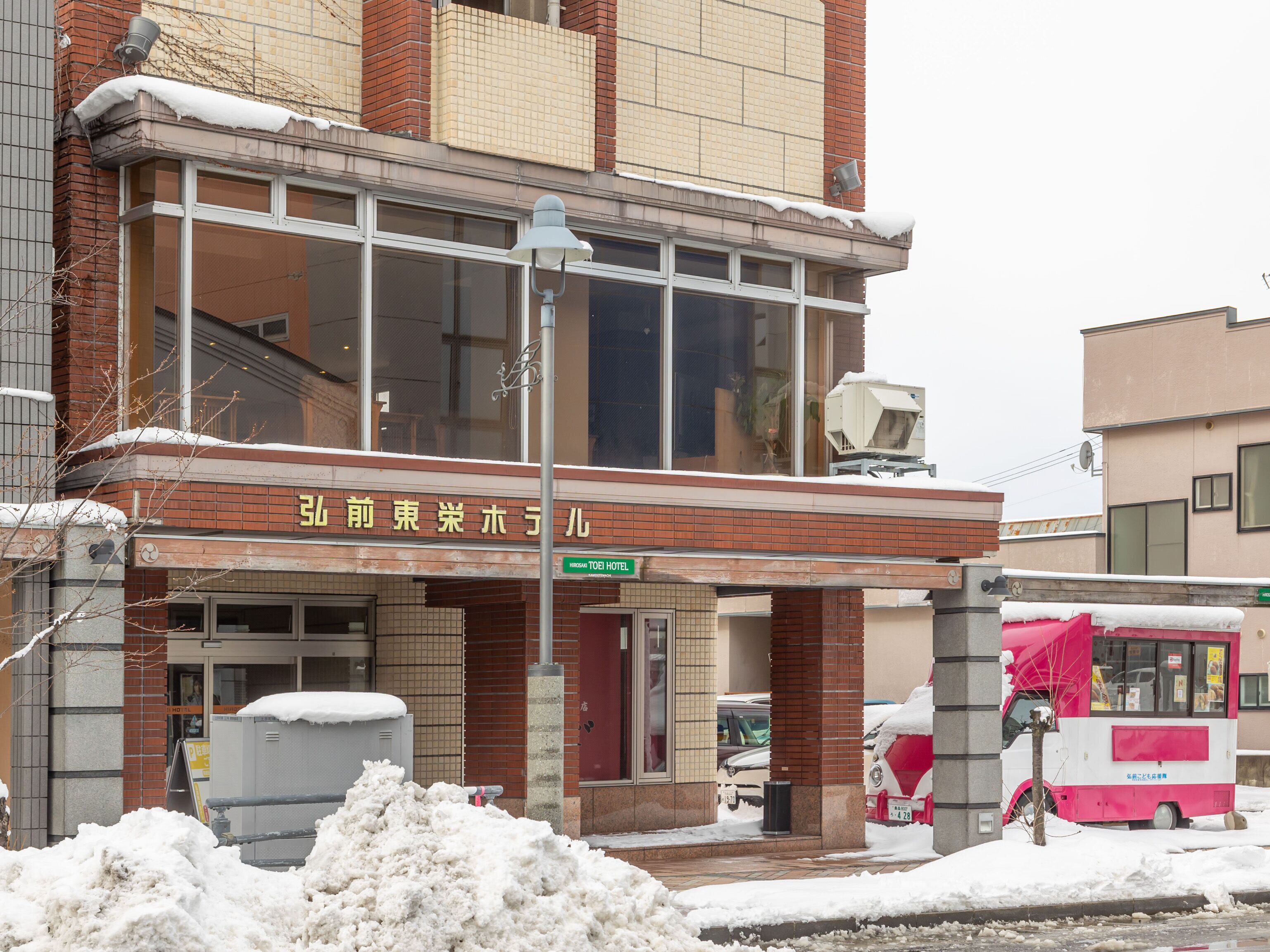 A hotel with a brick facade, large windows, and a sign in a foreign language.