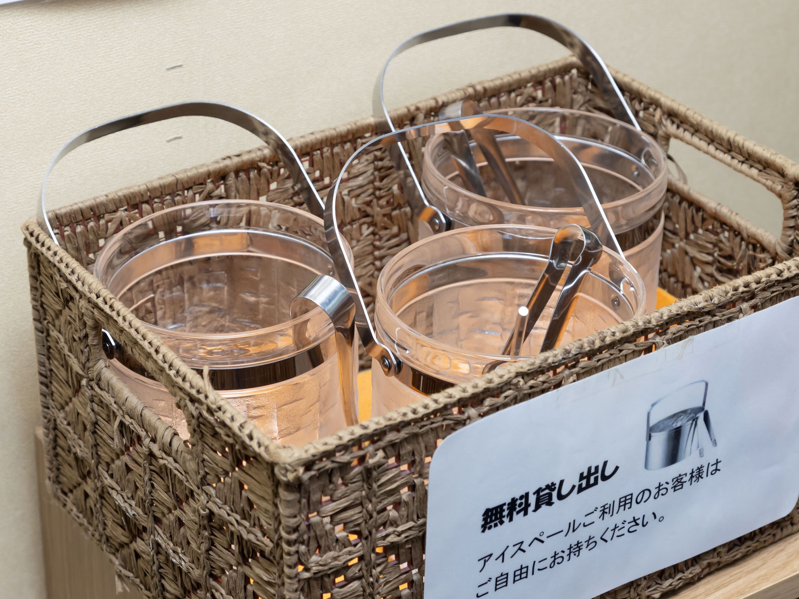 Un panier en osier contenant trois verres transparents en verre avec des anses en métal, ainsi qu’une pancarte avec du texte en japonais.