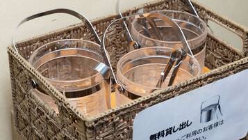 Un panier en osier contenant trois verres transparents en verre avec des anses en métal, ainsi qu’une pancarte avec du texte en japonais.
