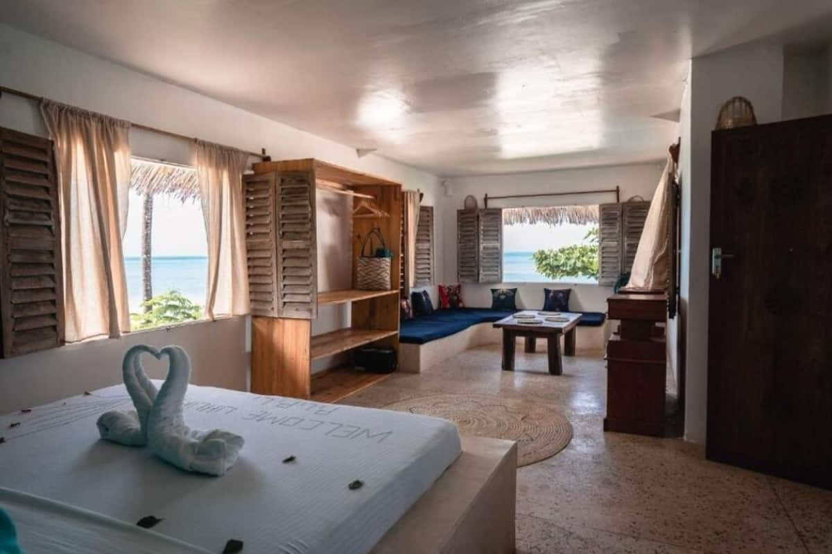 Una habitación con cama, un armario de madera, una zona de estar con vista al mar y una mesita.