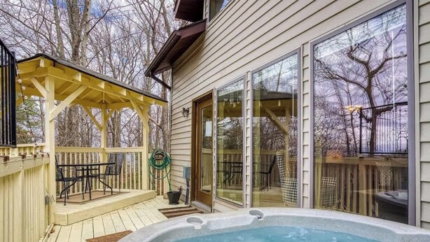 A backyard with a hot tub, a covered patio, and a deck.
