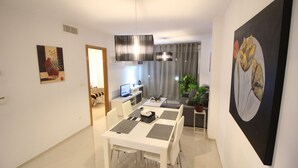 Un comedor moderno con una mesa y sillas blancas, una lámpara colgante y obras de arte en las paredes.