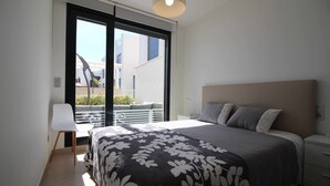 Ein Schlafzimmer mit einem Bett, einem Sessel, einem Nachttisch und einem großen Fenster.
