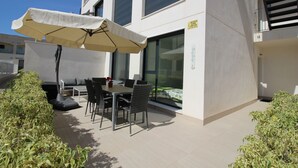 Eine Terrasse im Freien mit Tisch, Stühlen, einem großen Sonnenschirm und einer Couch.