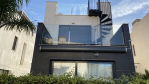 Un bâtiment moderne avec une façade noire, un balcon en verre et un escalier en colimaçon.