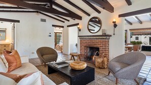 A cozy living room with a fireplace, wooden beams, and comfortable seating.