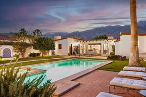 Un espace piscine doté d’une terrasse, de chaises longues et offrant une vue sur les montagnes.