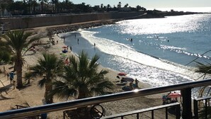 A beach with palm trees, umbrellas, and people. - Groundfloor Oasis Beach IX Punta Prima (Torrevieja)
