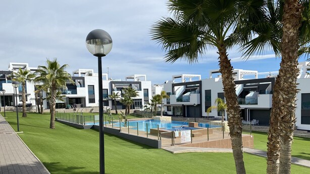 A modern hotel with a swimming pool, palm trees, and contemporary architecture. - Groundfloor Oasis Beach IX Punta Prima (Torrevieja)