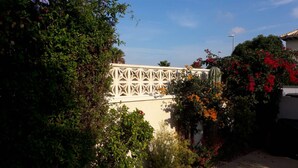 A white building with a geometric lattice structure, surrounded by dense foliage and flowering plants. - Family house Cuidad Quesada  Rojales (Ciudad Quesada)