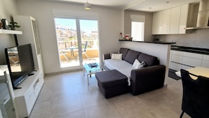 Et moderne køkken med spiseplads, sofa og TV.