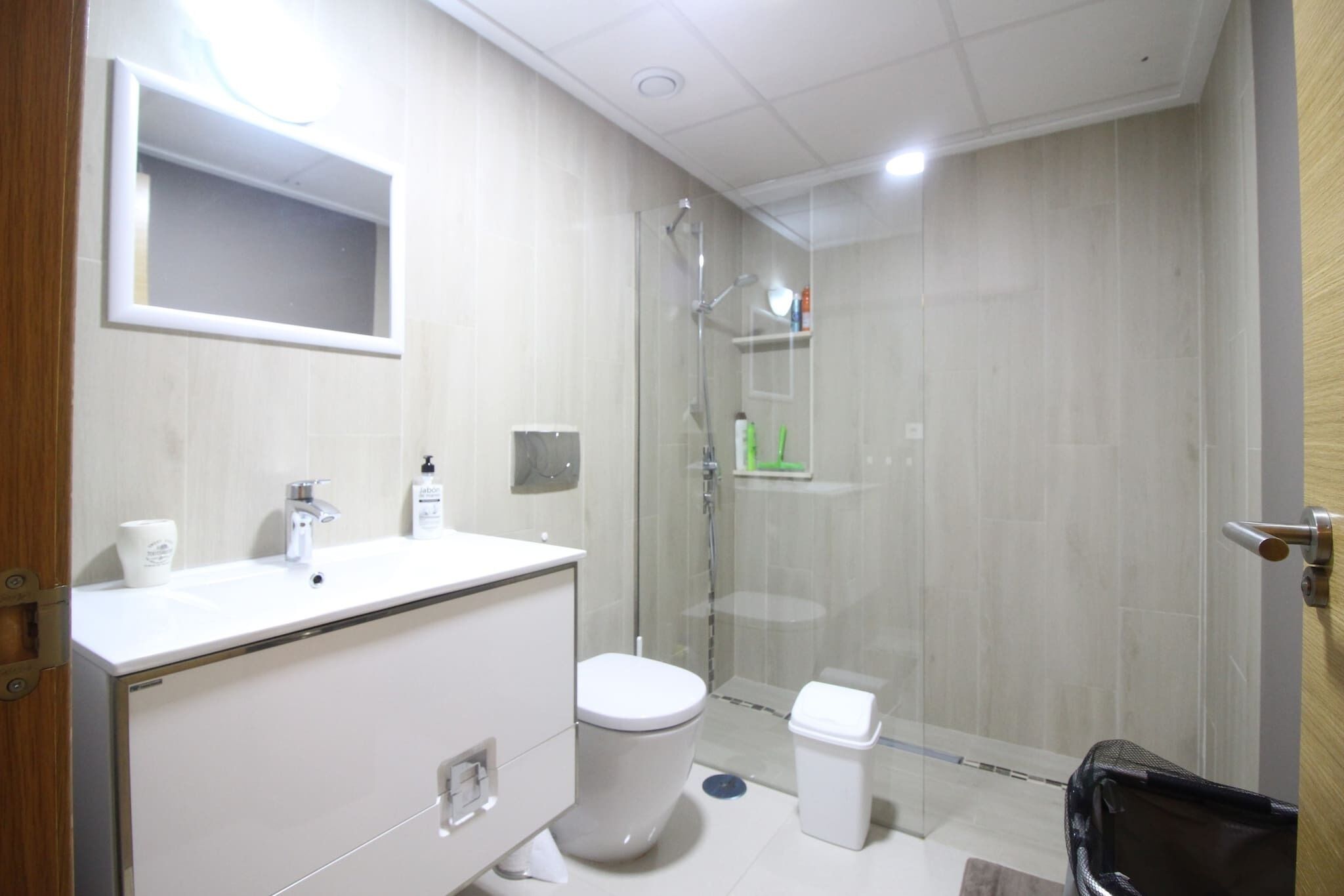 A modern bathroom with a white sink, toilet, and glass-enclosed shower.